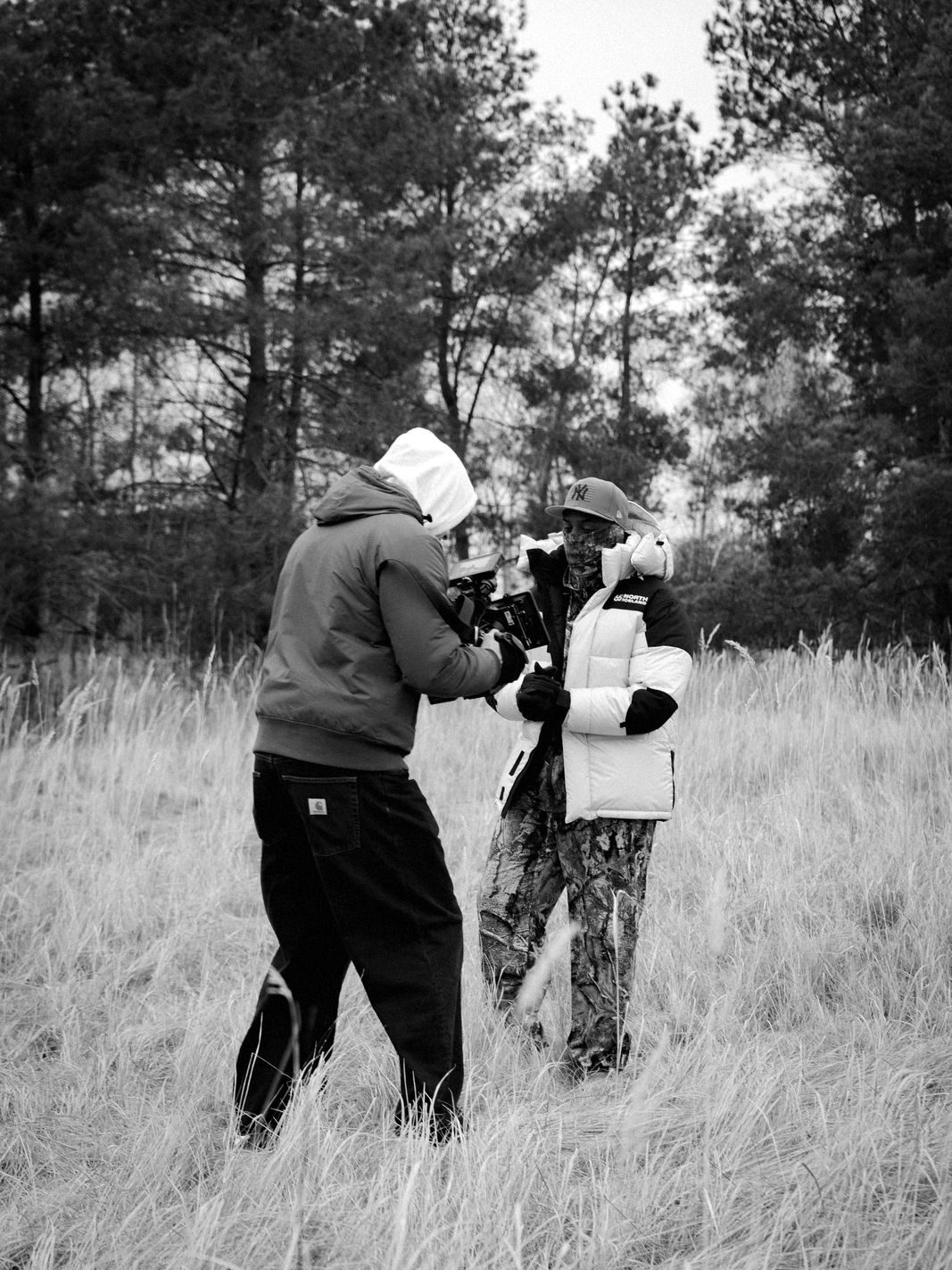 Two people filming in a field of tall dry grass